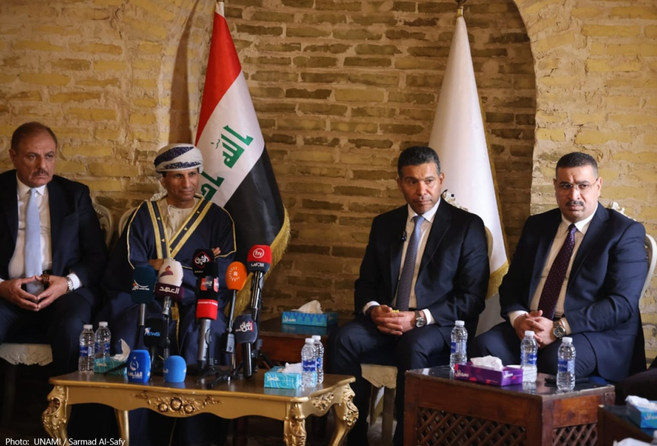 A group of men sitting in front of microphones

Description automatically generated