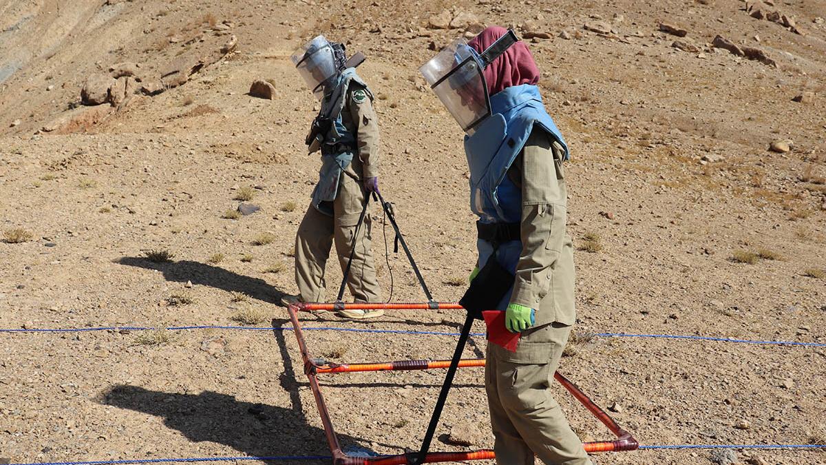 Two female deminers searching for sub-surface explosive remnants of war.