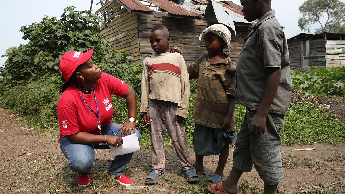 a woman with UNMAS T-shirt is talking to three children
