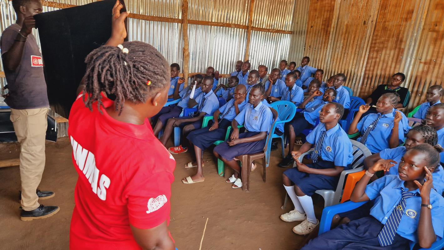 a woman and a man are presenting a poster to a class of students