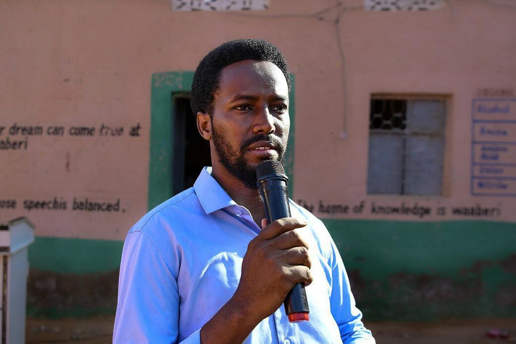 Mohamed Sheikh Said Haji speaks with a microphone in front of a school Mohamed Sheikh Said Haji speaks with a microphone in front of a school