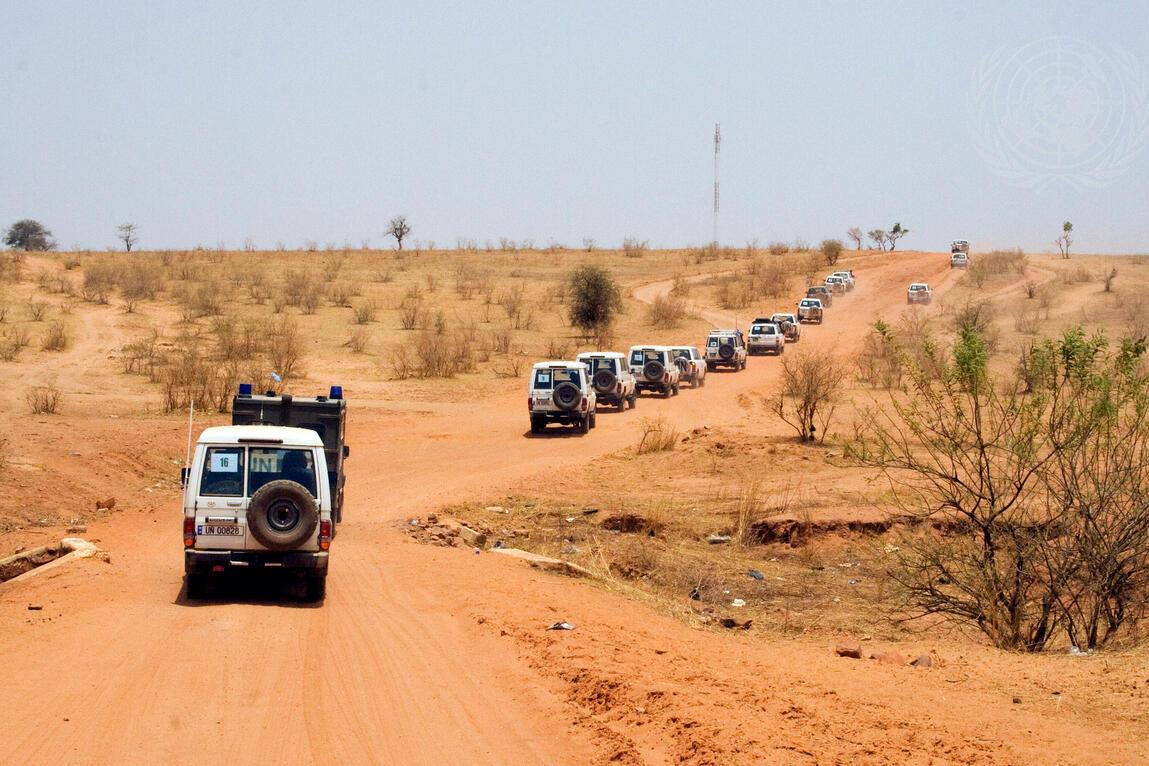 A United Nations convoy escorts an African Union delegation of former Presidents of African countries on their way to visit the Djabal Refugee Camp. A convoy of UN four wheel drive vehicles along a red dirt road.