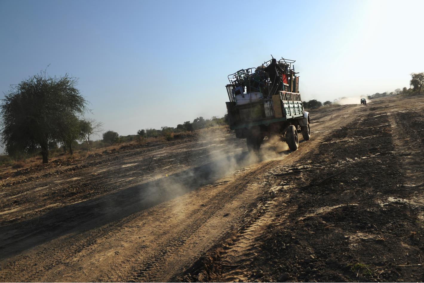 Open back lorry full of objects driving away on a dirt road