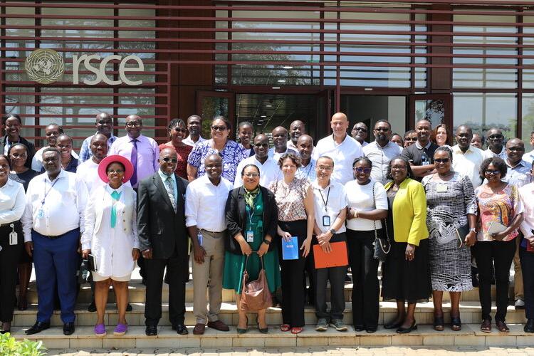 A group of people standing on steps in front of a building with the word "RSCE" behind them. They are smiling.