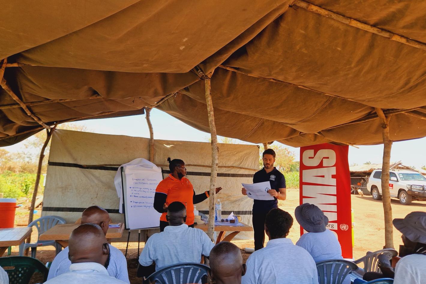 a man and a woman are standing in front of a couple of deminers sitting in chairs.