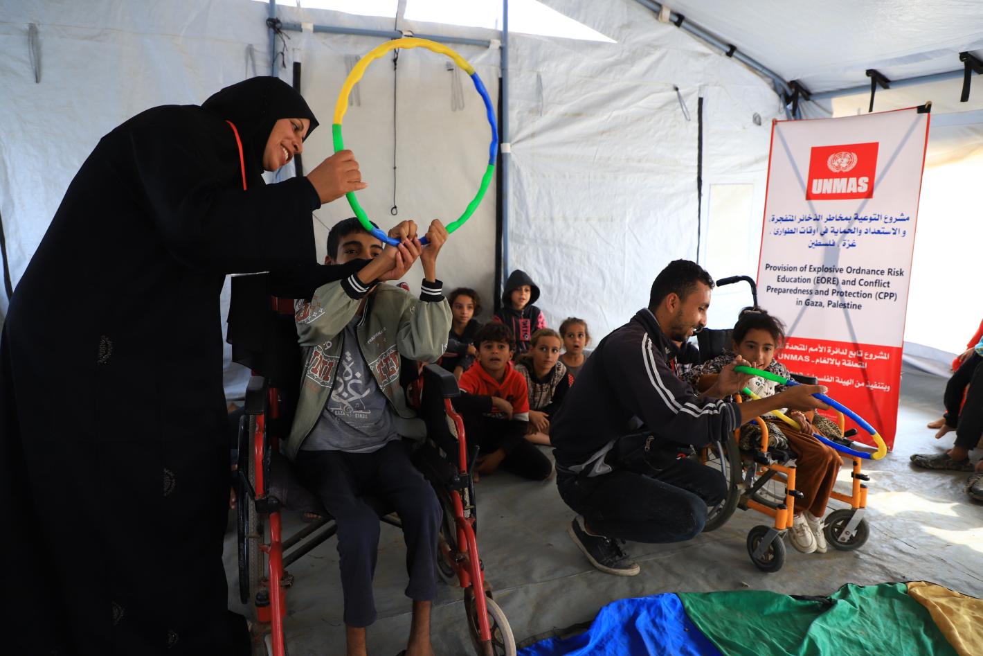 children with disabilities participate in a risk education session where facilitators teach about explosive threats using colourful toys.