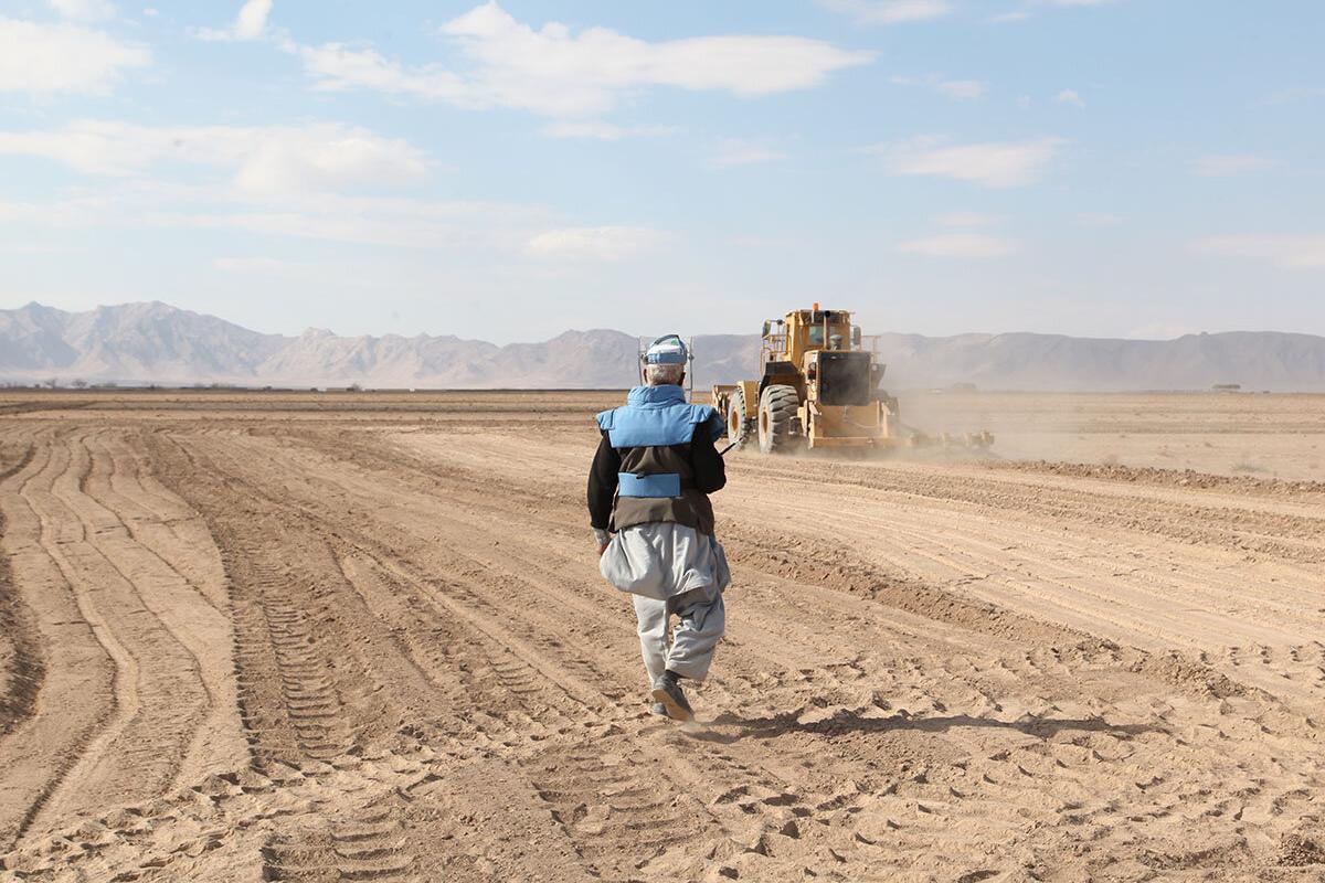 a deminer is in a field with a truck in the background