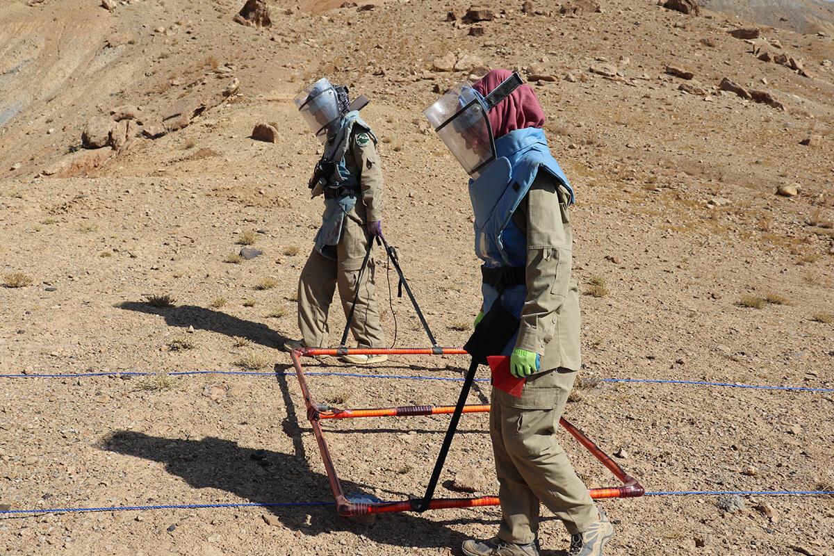 Two female deminers searching for sub-surface explosive remnants of war.