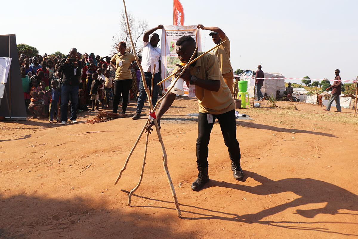 A Community Liaison Officer is illustrating the marking of a suspected explosive item with tree branches