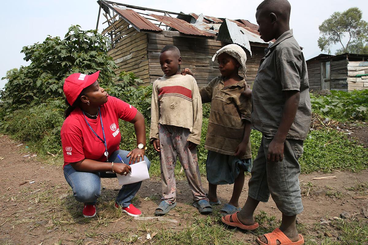 a woman with UNMAS T-shirt is talking to three children