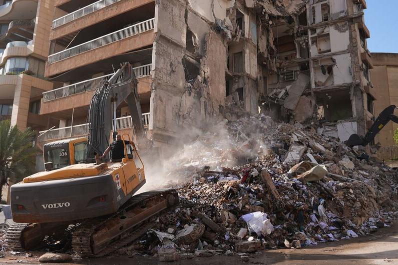 Heavy machinery clears rubble from a building destroyed by airstrikes in Beirut, Lebanon.