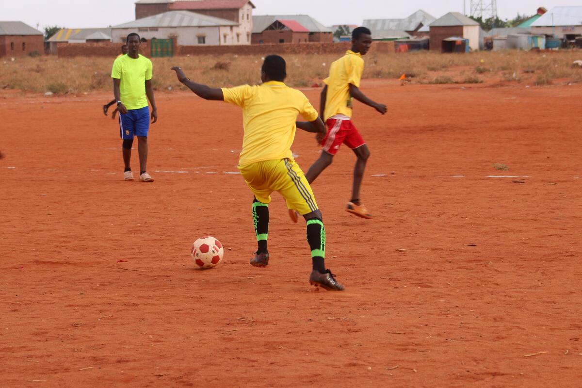 Youth playing football on a recently cleared parcel of land
