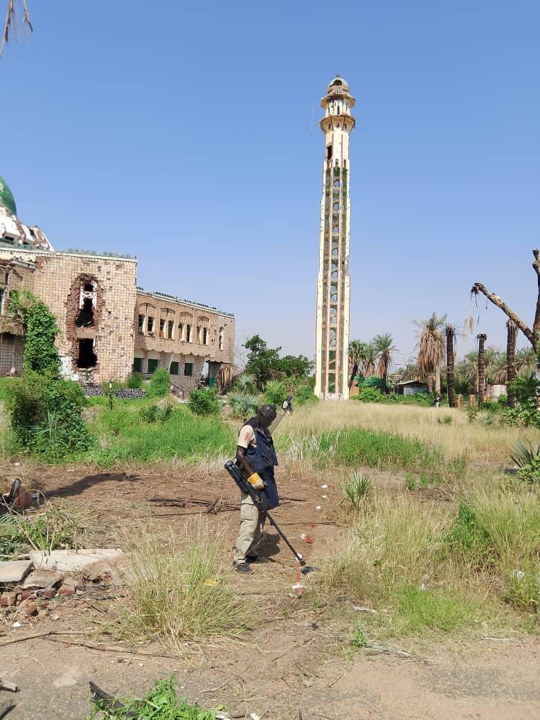 a deminer is holding a detector in a field