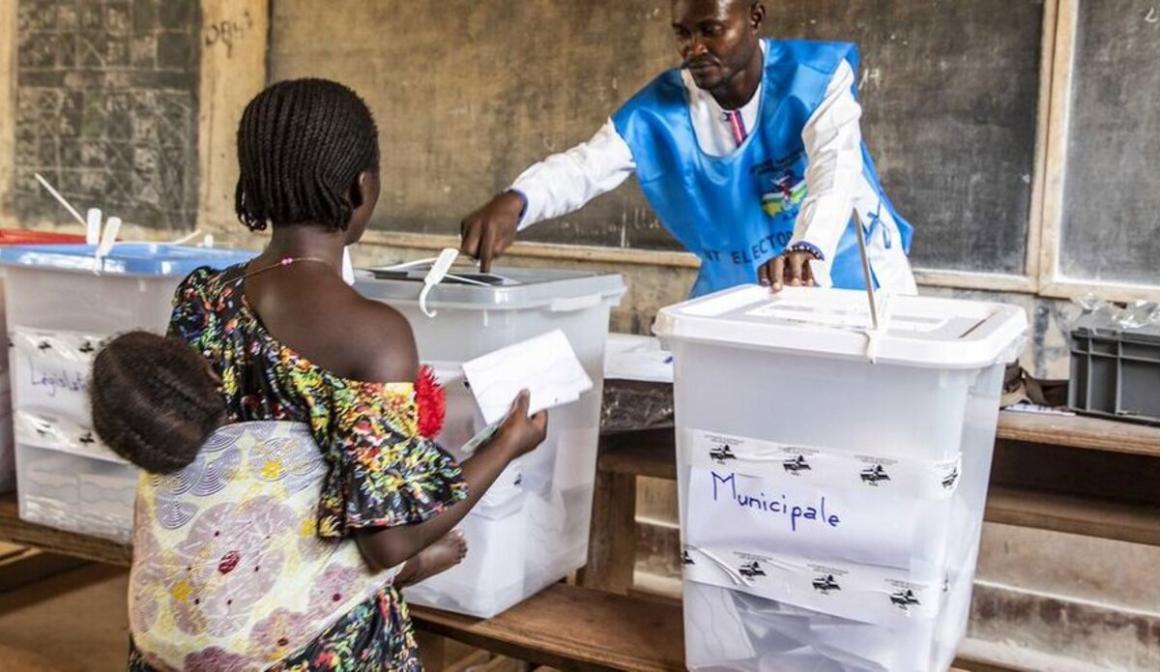A woman, carrying a baby, casting her votes during the elections.