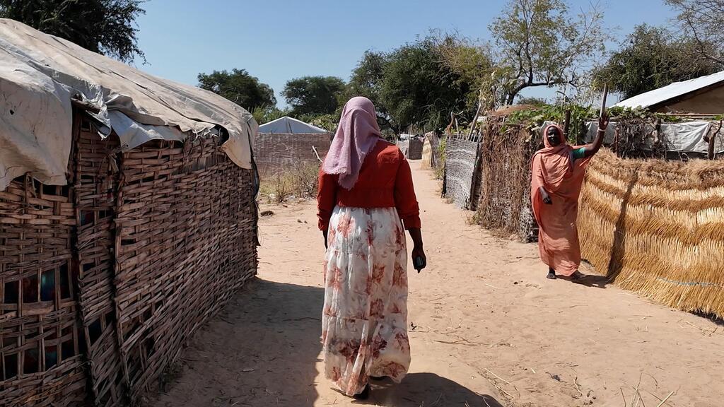 Woman standing in front of village houses.