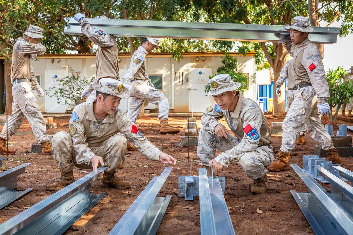 Un groupe de soldats transporte et examine de grandes poutres métalliques