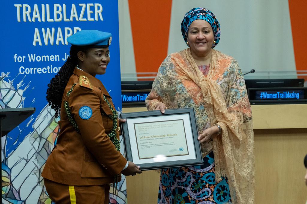 UN Deputy Secretary General presenting the 'Trailblazer Award for Women in Corrections' event. The Deputy Secretary General is wearing traditional attire while the recipient is wearing their policing peacekeeping uniform.
