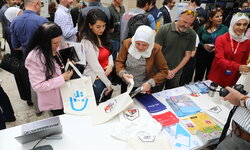 A group of people are standing in front of a booth, looking at the brochures on the table.