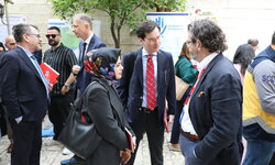 Three people wearing suits are chatting with each other.