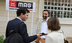 Three people are chatting with each other in front of a sign.