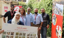 Six people are standing together beside a red banner