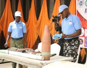 Two men standing around a table of exhibit explosive ordnances